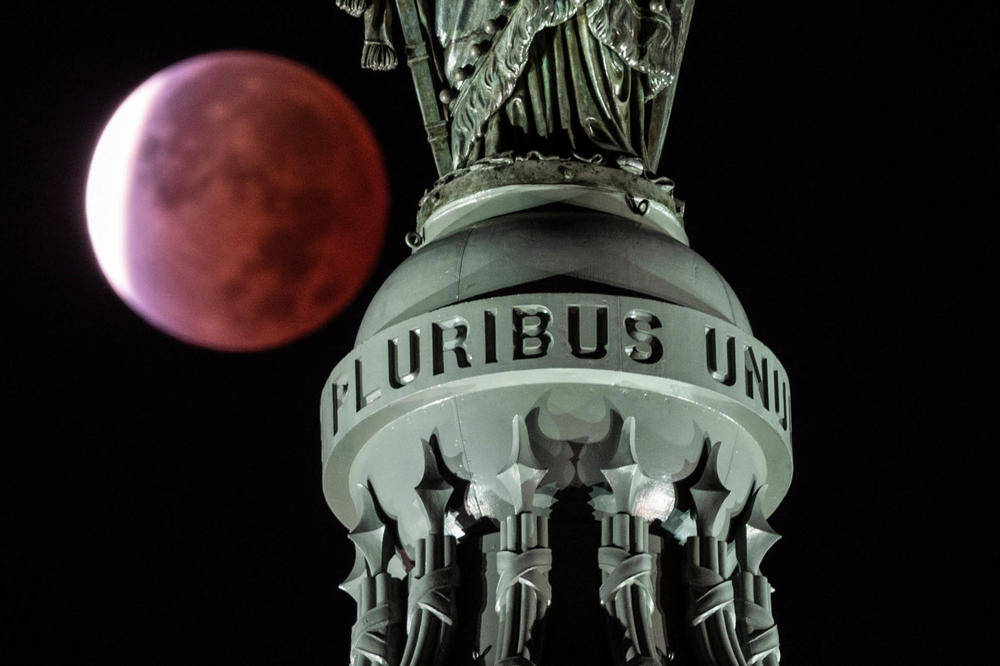 The moon, with a partial lunar eclipse, is seen behind the writing E Pluribus Unum, latin for 