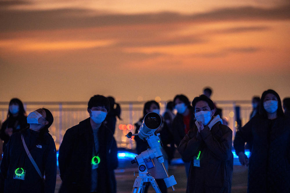 People look on by a telescope as people gather to observe a lunar eclipse from the observation deck of Roppongi Hills in Tokyo on Nov. 19.