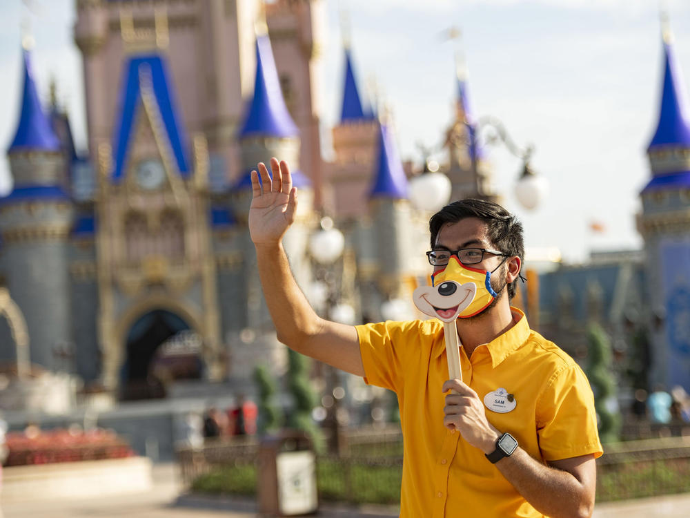 A Disney employee welcomes guests to Walt Disney World Resort on July 11, 2020 in Lake Buena Vista, Fla. Disney has paused its COVID-19 vaccine mandate to comply with a new Florida law.