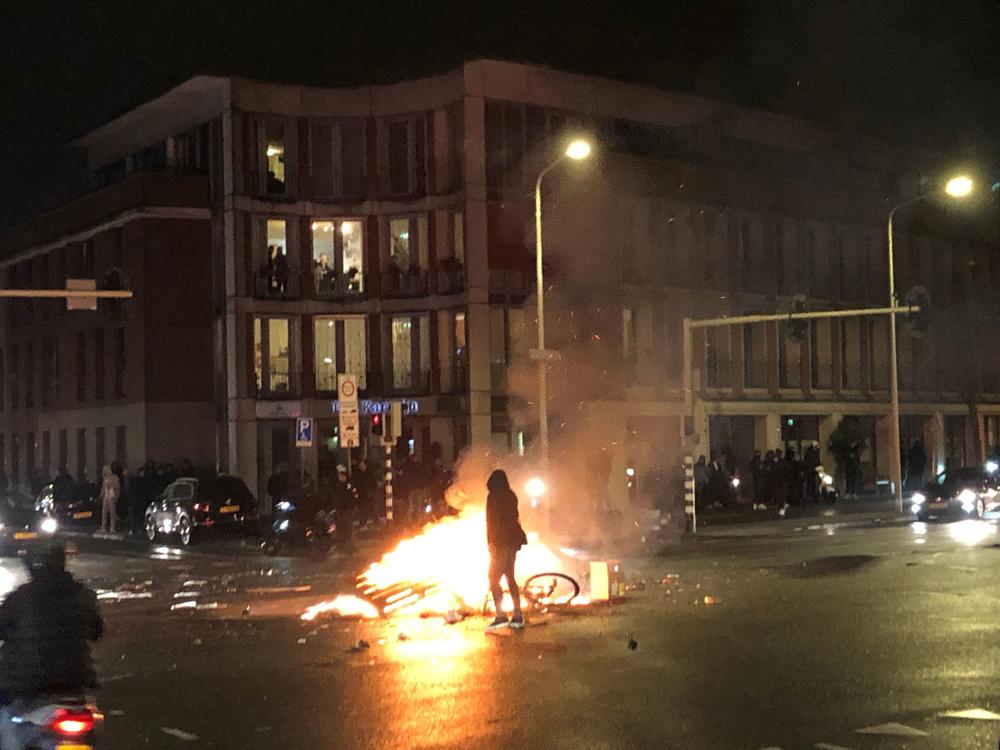 A man walks in front of a fire in a street of The Hague during a demonstration against the Dutch government's coronavirus measures on November 20, 2021.