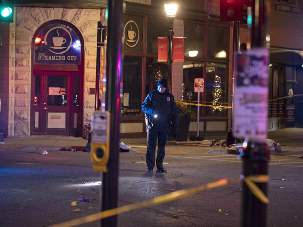 A police officer uses a flashlight while looking for evidence in downtown Waukesha, Wis., after an SUV sped through a barricade and slammed into a Christmas parade, killing and injuring several people on Sunday.