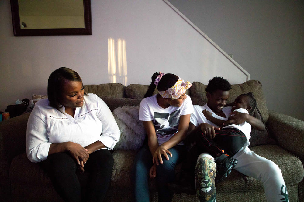 Maryanne Lundy, left, and her children, Malaysia Hill, Meliq Hill and Cornelius Madison sit on their couch in their home on Friday, Nov. 19, 2021 in Indianapolis.