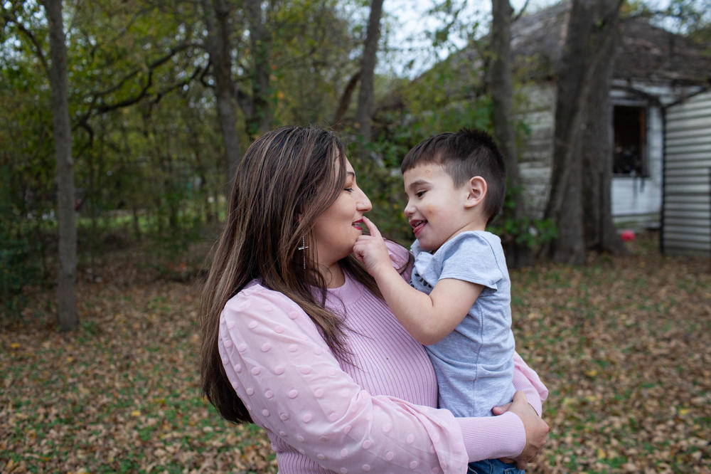 Ramona Bravo holds Azaiah, 2, in front of their house. Bravo spent 23 years in an abusive relationship and then lived at her parent's house.