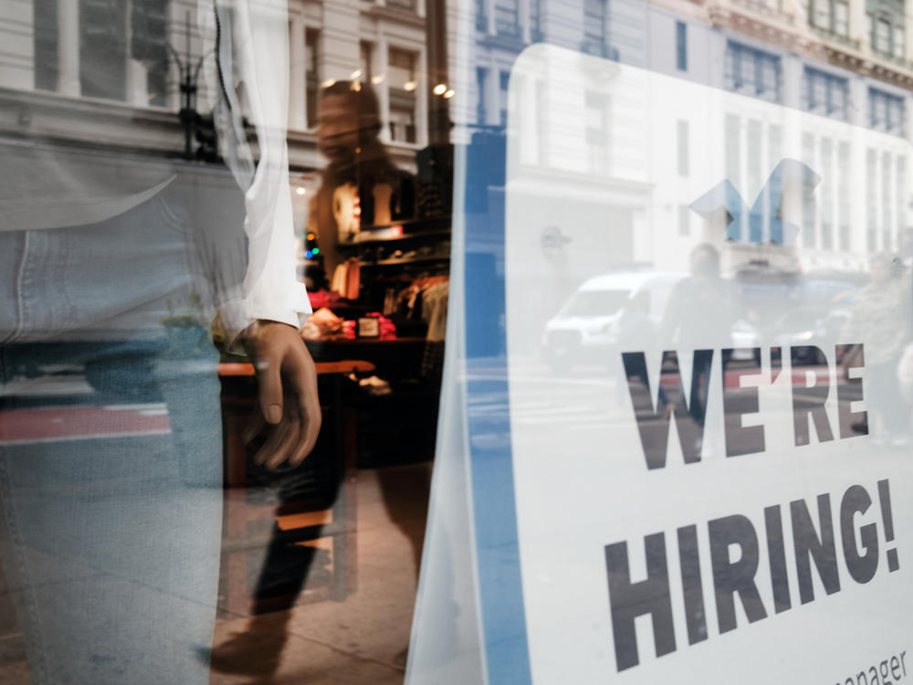 People walk by a hiring sign in a store window in New York on Nov. 17.