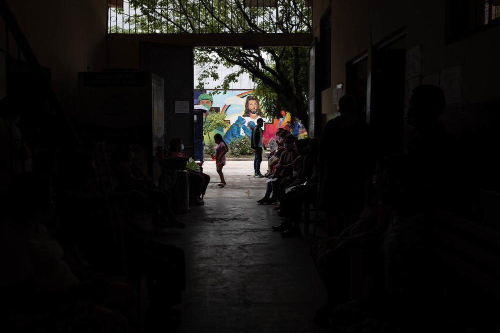 People wait outside the medical clinic of the priest and doctor, Raymond Portelli, located in the San Martin de Porres church in Iquitos, Peru. Portelli sees 30 patients a day and says he now rarely sees COVID cases.