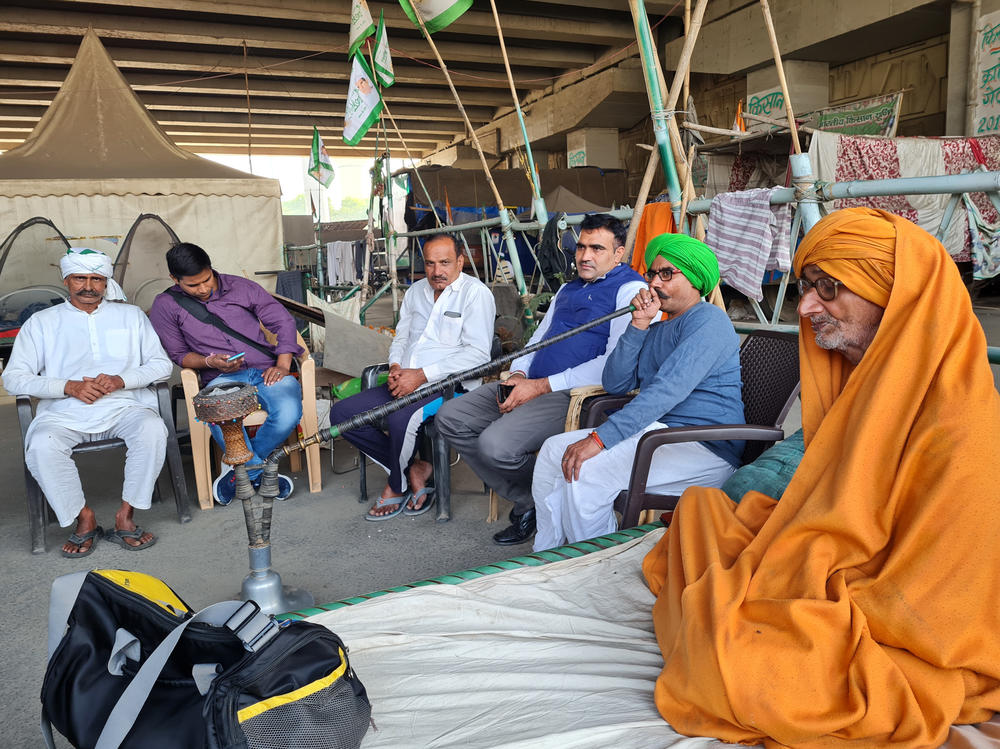 Ramkumar Pagdiwale, in a green turban, smokes a traditional hookah pipe from his home state of Uttar Pradesh. Pagdiwale is a sugarcane farmer who's spent the past year camping out in the Indian capital, protesting Prime Minister Narendra Modi's new farm laws.