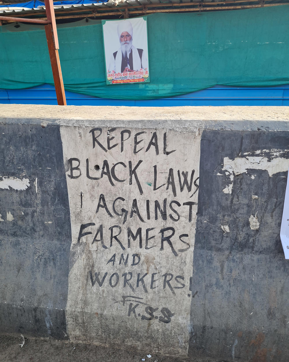 Pro-farmer graffiti on a highway barricade near Ghazipur, where Indian farmers have been camping out for a year, protesting against Prime Minister Narendra Modi's farm laws.