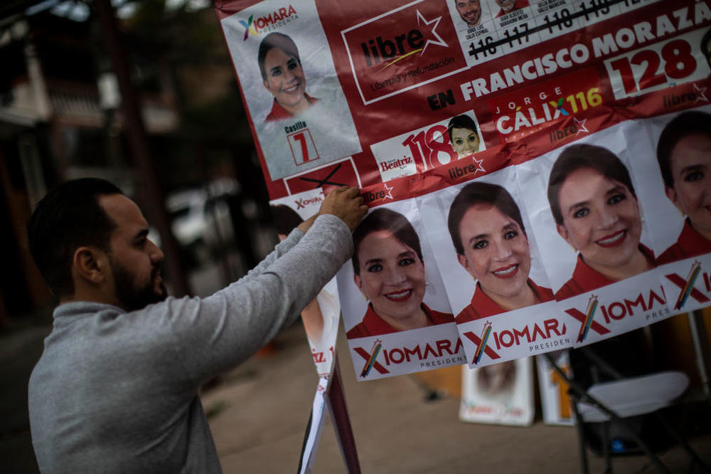 A supporter of the leading presidential candidate, Xiomara Castro, hangs campaign posters on Saturday in Tegucigalpa, Honduras.