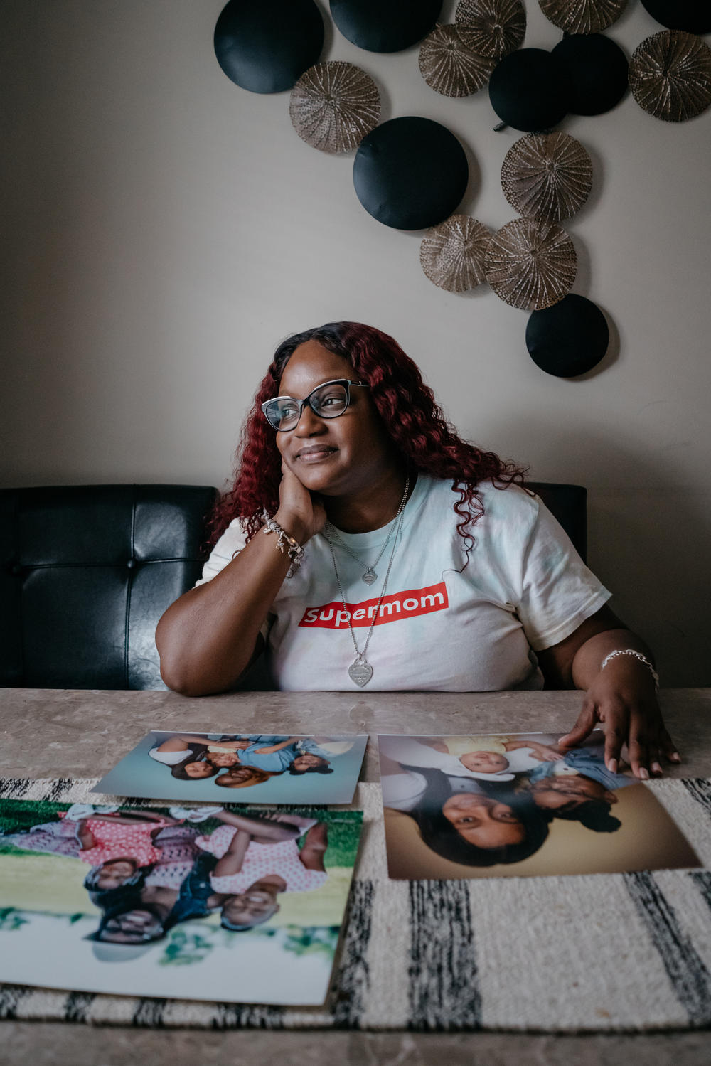 Cassie looks at family photos at her kitchen table. One is from when she was living in a transition home for women fleeing domestic violence, and more recent photos taken after her youngest daughter was born.