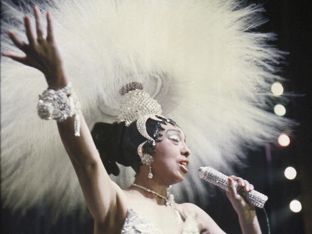 Josephine Baker holds a rhinestone-studded microphone as she performs during her show 