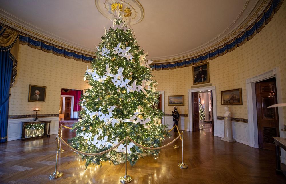 A White House military social aide stands near the official White House Christmas tree in the Blue Room during a press preview of the White House's holiday decorations on Nov. 29.