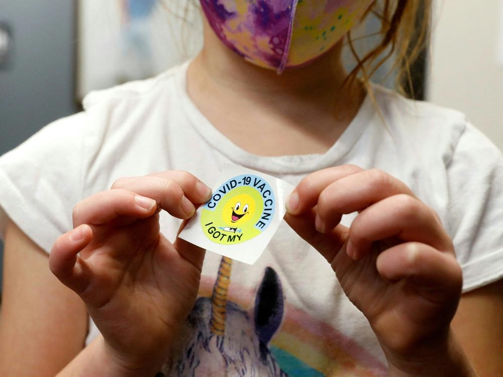 A 6 year-old child holds a sticker she received after getting the Pfizer-BioNTech COVID-19 vaccine at the Child Health Associates office in Novi, Mich., on Nov. 3.