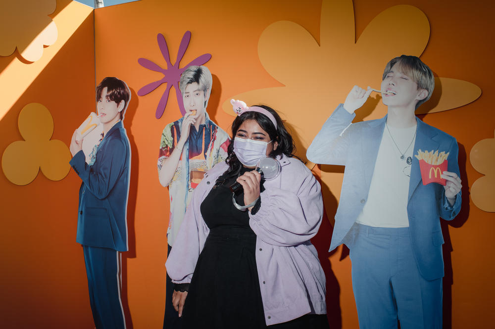 Abi Castaneda, 25, stands with McDonald's cutouts of BTS members V, RM and J-Hope.