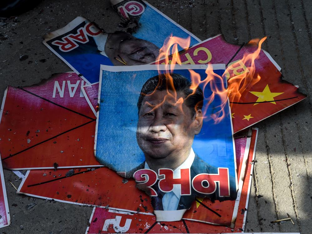 Members of the National Students' Union of India burn a poster showing Chinese President Xi Jinping during an anti-China demonstration in Ahmedabad on June 18, 2020.