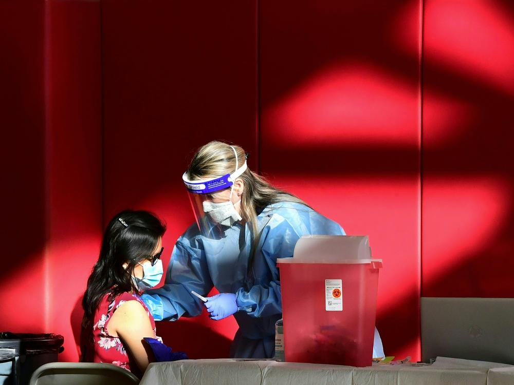 A registered nurse administers the COVID-19 vaccine at a high school gym in Corona, California. Scientists are trying to determine if vaccines (and boosters) will offer protection against the newly identified omicron variant.