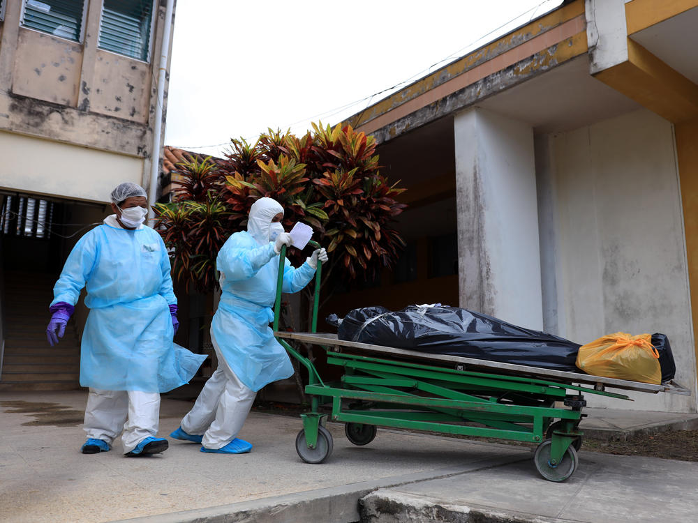 Health care workers take deceased COVID-19 victims to the morgue at Felipe Arriola Iglesias Hospital in Iquitos on May 4, 2020.