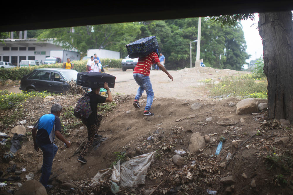 Young men carry luggage from Venezuela into Colombia under the Simón Bolívar International Bridge. Millions of Venezuelans have left the country in recent years.