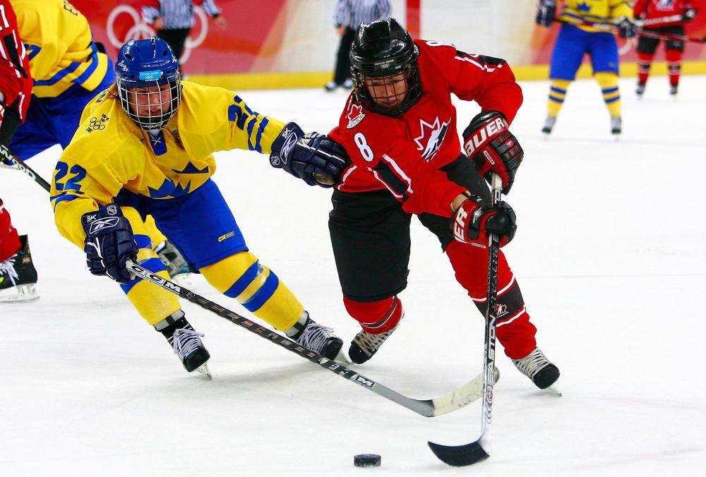 Katie Weatherston, right, fights for the puck against Sweden during the final game of the women's ice hockey tournament at the 2006 Winter Olympic Games in Turin, Italy.