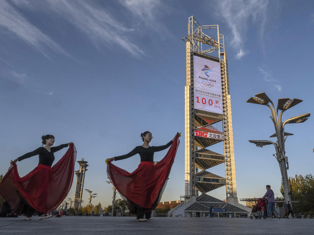 Women practice a dance routine on Oct. 27 in front of a large countdown screen showing 100 days before the opening of the Beijing 2022 Winter Olympics.