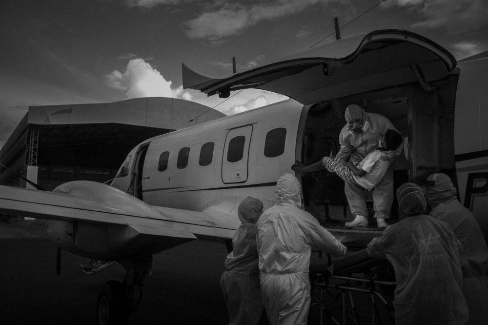 Health workers carry a 10-year-old patient in serious condition with COVID-19 from a flight organized by Amazonas state's aerial intensive care unit. The patient was transferred from Santo Antônio do Içá more than 500 miles to Eduardo Gomes Airport in Manaus, Brazil, on May 22, 2020.