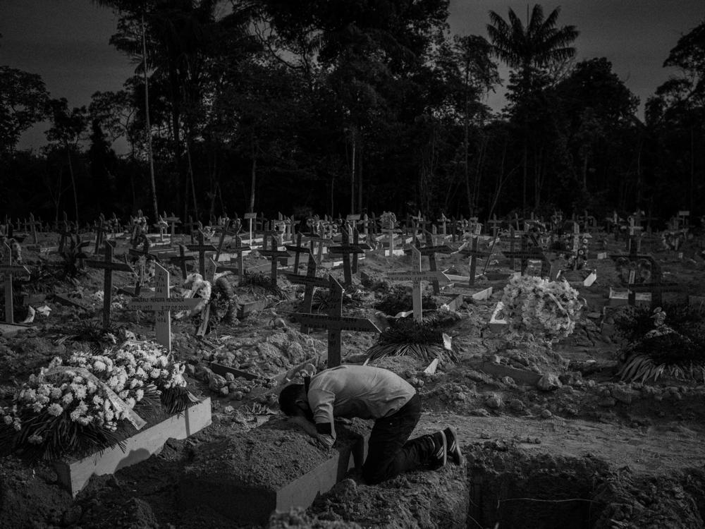 A man cries over his mother's grave in the Nossa Senhora Aparecida cemetery, in Manaus, Amazonas, Brazil, on Sept. 29, 2020. Iris Gonçalves Alves died at age 54 the previous day from COVID-19, according to the information on her burial record. During the worst times of the pandemic in Manaus, only three relatives could attend a burial in its cemeteries.