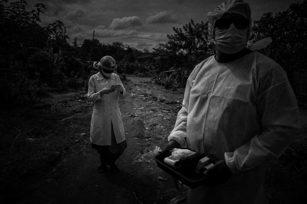 Nursing technician Vanda Ortega, 33, from the Witoto people, and the university nursing student Francineldo (right), 45, from the Kokama people, walk in the Parque das Tribos (Park of Tribes), the only Indigenous neighborhood in Manaus, looking for people with symptoms and explaining safety measures against COVID-19, on Feb. 11, 2021.