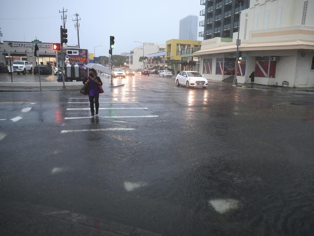 A pedestrian tries to cross a flooded Queen Street, Monday, Dec. 6, 2021, in Honolulu.