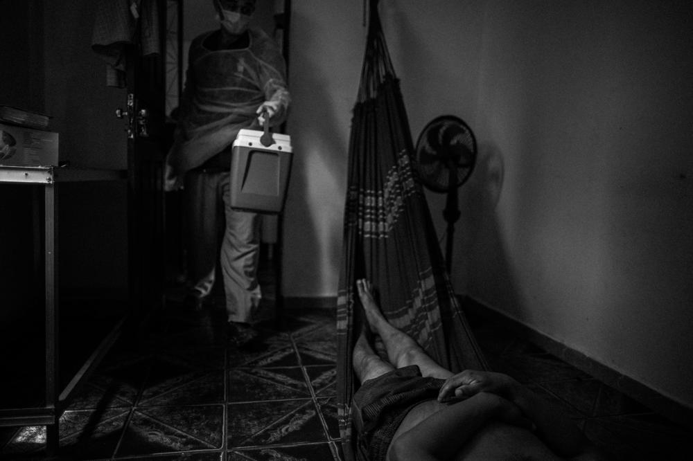 A worker with the municipal health department's death certificates office visits a residence to take a coronavirus test of the body of a man who died at home, in Manaus, on Jan. 15, 2021. Manaus collapsed during the pandemic: The number of dead in homes grew, and families lined up for a certificate that allowed them to bury their relatives.