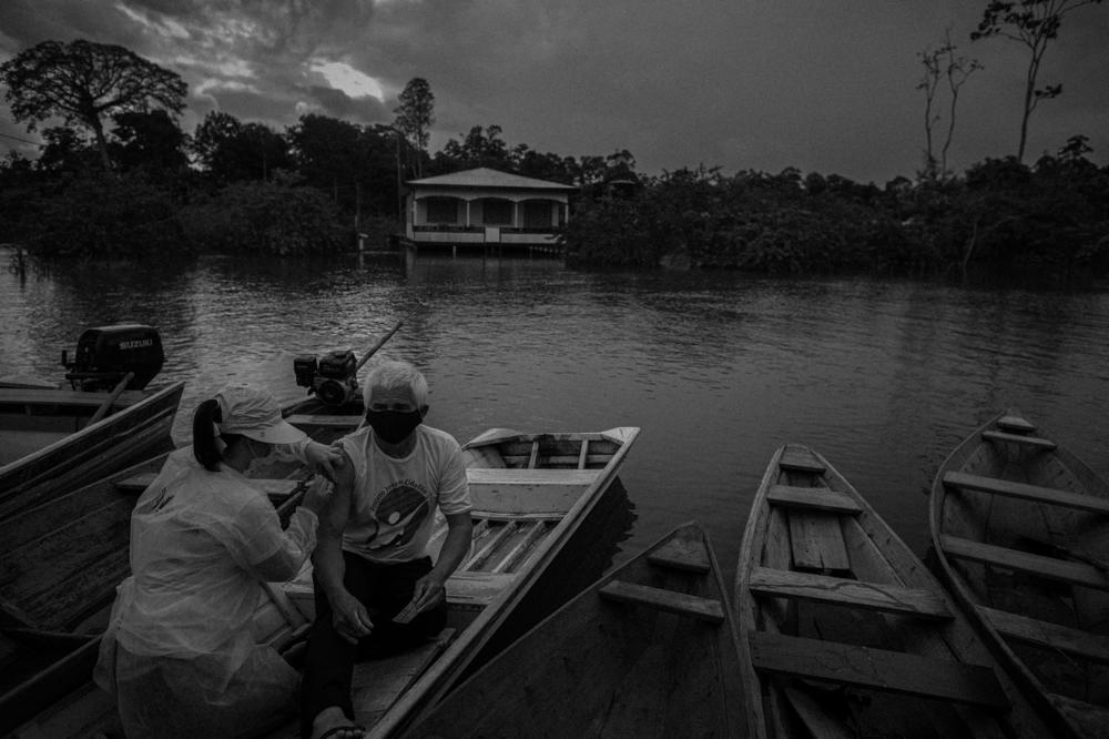 Nurse Taylline Bastos, 25, coordinator of the National Immunization Program in the municipality of Anama, about 100 miles from Manaus, administers a dose of the AstraZeneca vaccine, on May 27, 2021. People in the Vila do Cuinha community went to their vaccination appointment by boat, as they were dealing with major river flooding in Anama.