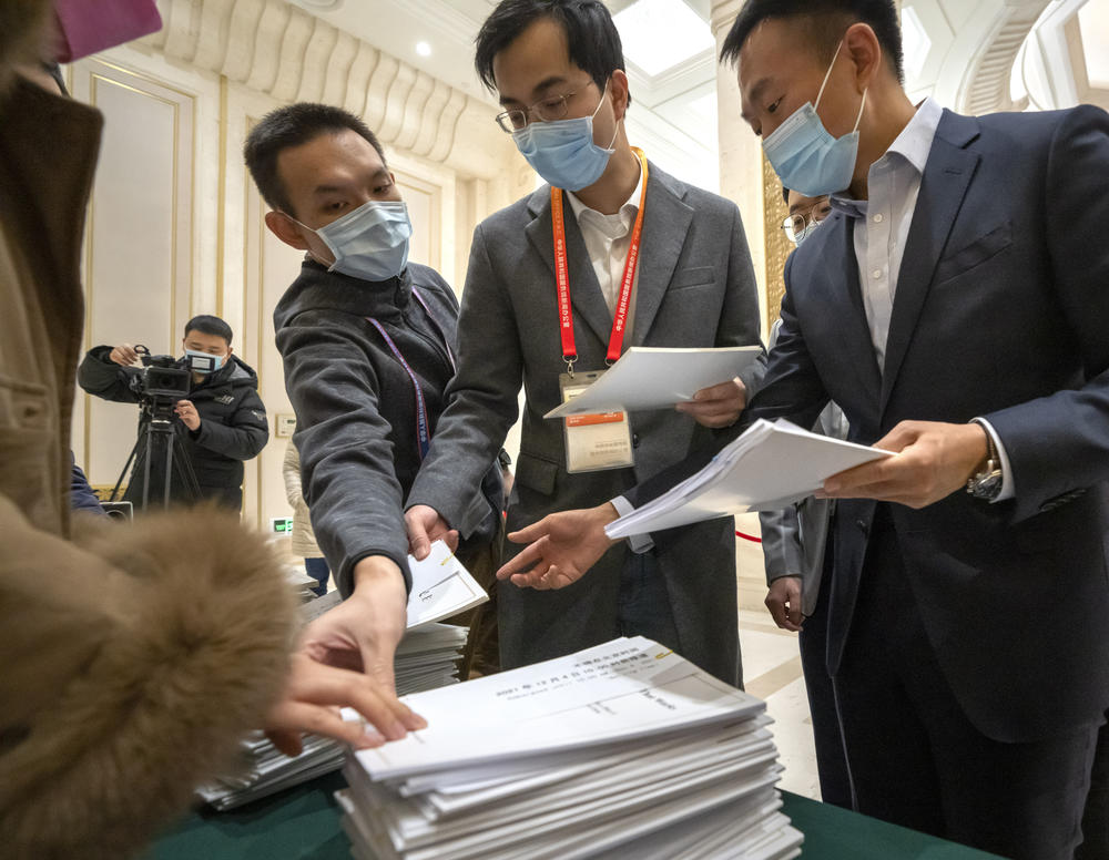 Journalists reach for copies of a Chinese government-produced report titled 