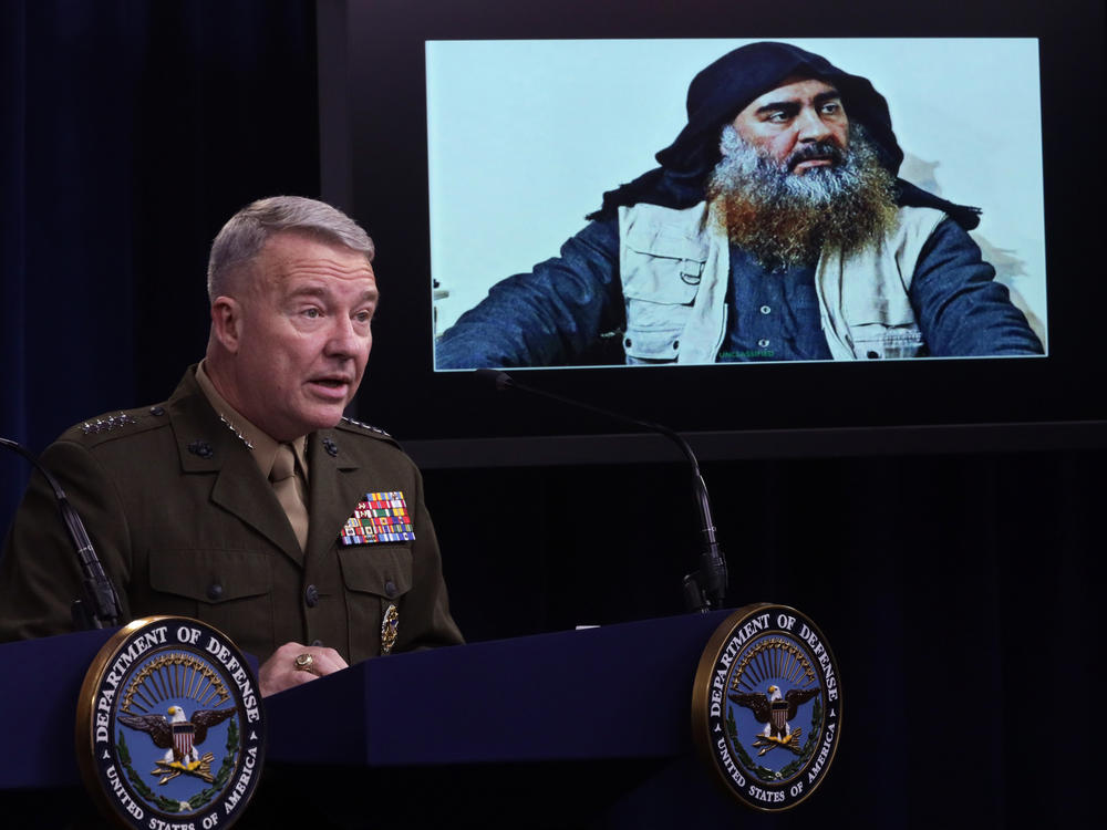 Marine Corps Gen. Kenneth McKenzie, commander of U.S. Central Command, speaks as a picture of Abu Bakr al-Baghdadi is displayed during a news briefing on Oct. 30, 2019, at the Pentagon in Arlington, Virginia. McKenzie spoke to reporters to provide an update on the special operations raid that targeted the Islamic State leader in Idlib province, Syria.