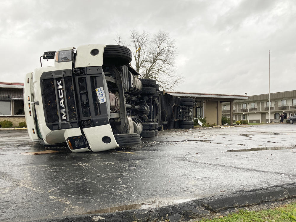 A large semi is flipped over and pushed against a building in Bowling Green, Ky., on Saturday.