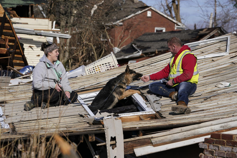 <strong>Sat., Dec. 11:</strong> Chris Buchanan, right, lures dog Cheyenne from a tornado-damaged home with help from Niki Thompson, left, in Mayfield, Ky.