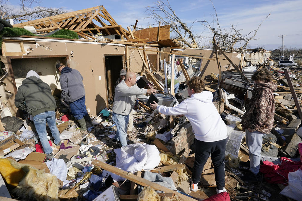 <strong>Sat., Dec. 11:</strong> People help retrieve items from a destroyed home in Mayfield, Ky.
