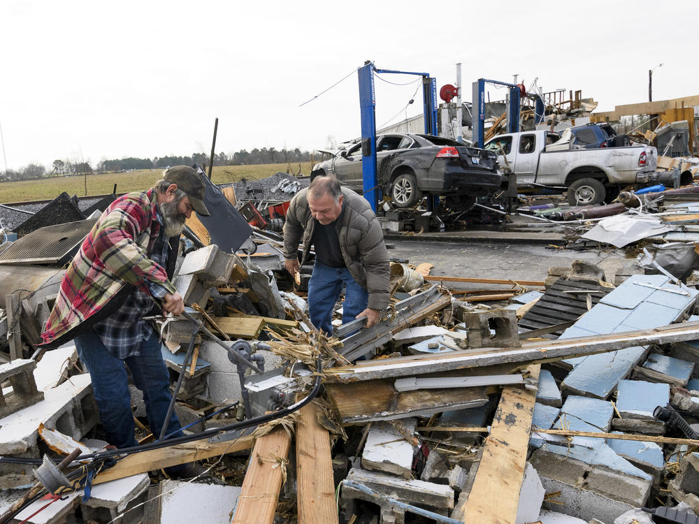 Martin Bolton (left) and shop owner Danny Wagner try to shut off a leaking gas meter on Saturday after his automobile repair shop was destroyed by a tornado in Mayfield, Ky.