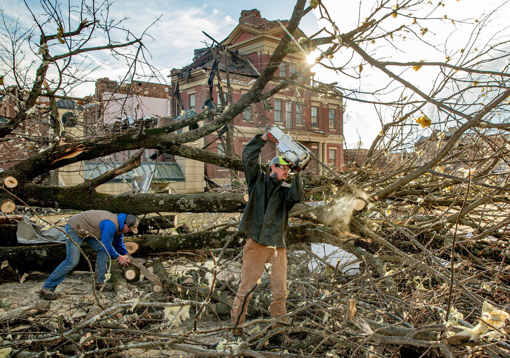 <strong>Sat., Dec. 11:</strong> Duke Traux, 33, of Elizabethtown, Illinois, cuts a downed tree with a chainsaw while Isaiah Keys, 18, of McCracken, Kentucky, picks up pieces in Mayfield, Kentucky.