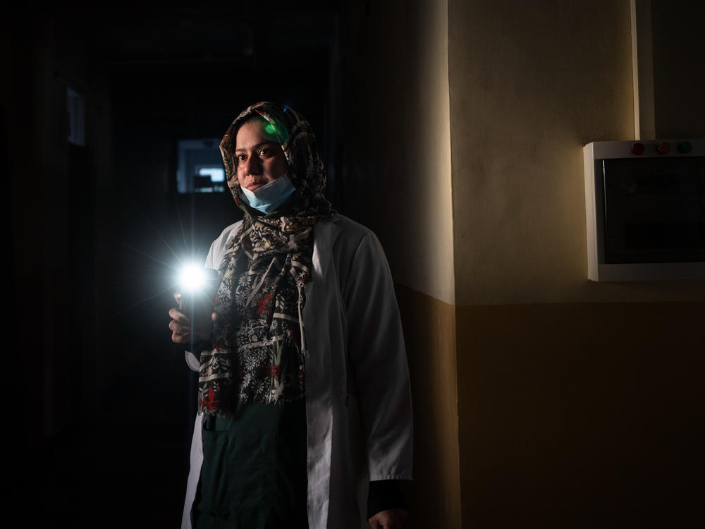 Dr. Elaha Ibrahimi uses her phone as a flashlight during a power cut inside the hospital in Mirbacha Kot, Afghanistan, in October. Health care workers have continued to work without salaries, without medicine for patients and with frequent power cuts.