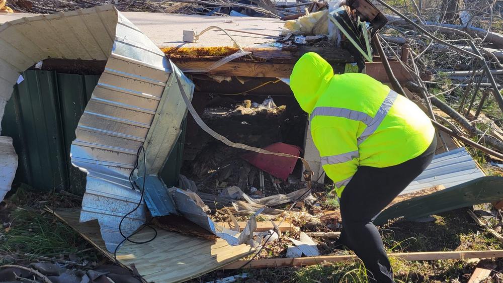 Bobbie Brown searches with her headlamp in the ruins of a shed. Her crew has already found the body of one man killed in the storm.