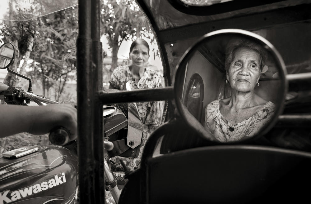 Isabelita Vinuya, 88, reflected in mirror, bids farewell to Perla Bulaon Balingit in the village of Mapaniqui in Pampanga. They are two of the last living 