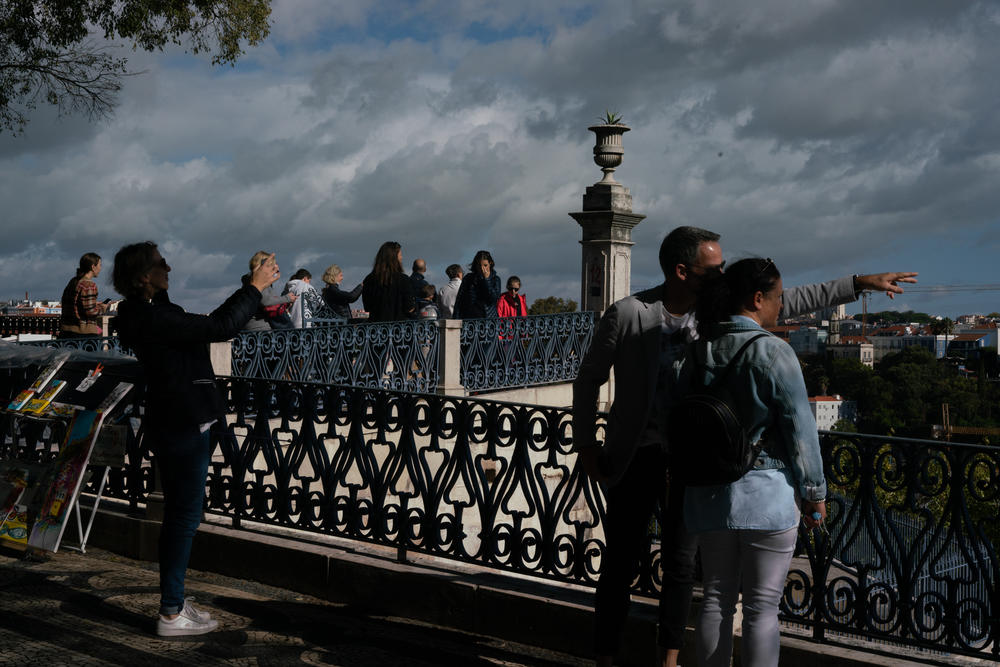 People look at the cityscape at the Miradouro de São Pedro de Alcântara in Lisbon, Portugal.