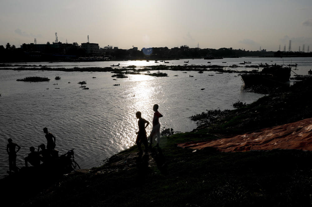 Two boys stand at the edge of the Buriganga River in Dhaka, Bangladesh, in July. A study finds that boys and young men made up two-thirds of all deaths among young people in 2019.