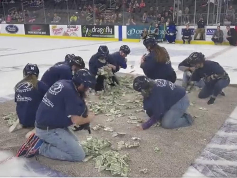 Area teachers in Sioux Falls, S.D., scramble to grab $1 bills on the ice rink at a Sioux Falls Stampede hockey game on Saturday, in this screenshot from a video posted by <em>Argus Leader</em> reporter Annie Todd that went viral this weekend.
