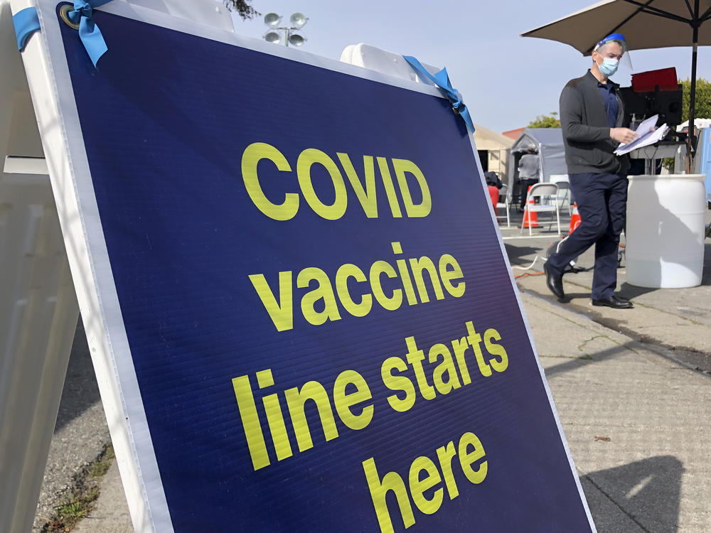 A sign is displayed at a COVID-19 vaccine site in the Bayview neighborhood of San Francisco on Feb. 8, 2021. California is exempting San Francisco from a rule that takes effect requiring all people to wear masks indoors.