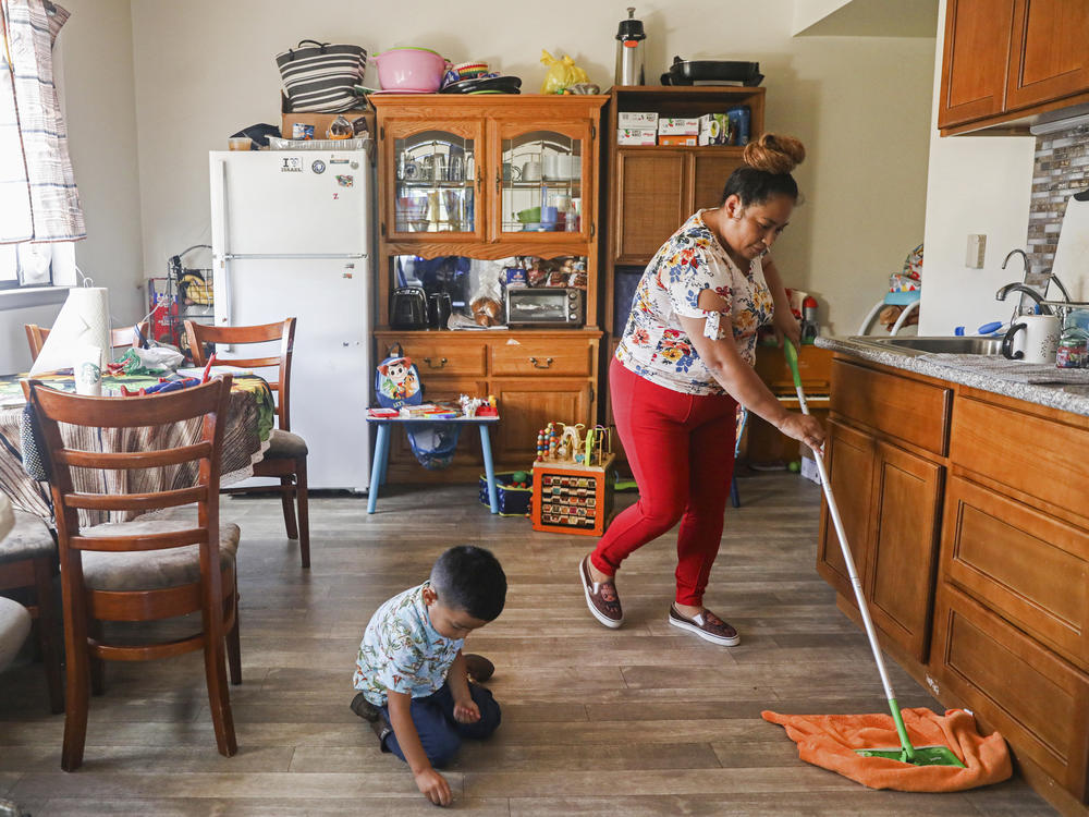 Mirna Arana mops the floor after playing with her son in her home in Oakland, Calif., Oct. 25, 2021. Arana works as a housecleaner in San Francisco and is hopeful about a proposed law that would give domestic workers paid sick leave.