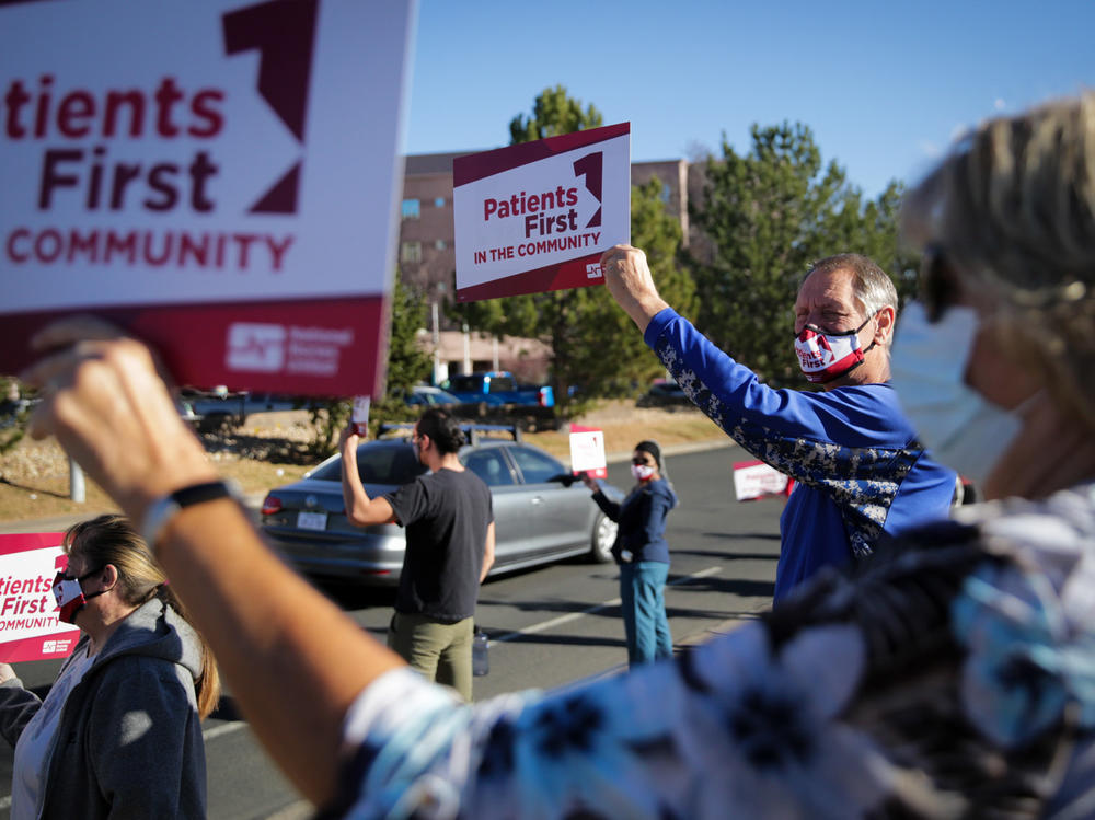 Longmont High School teacher and coach Jeff Kloster holds a sign in support of Longmont United Hospital nurses on December 2, 2021, outside the hospital. His wife Kris, a nurse there, was one of the speakers at the protest.