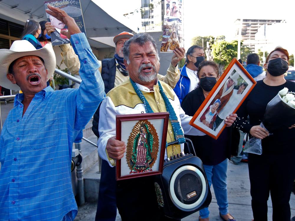 Fans of Mexican singer Vicente Fernández sing his songs as they hold his picture and the image of the Virgin of Guadalupe, outside the Country 2000 hospital where he died, in Guadalajara, Mexico, on Dec. 12.