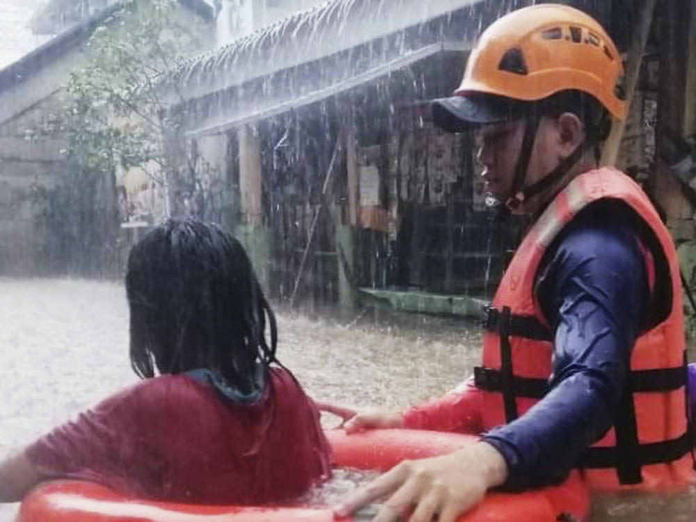 In this handout photo provided by the Philippine Coast Guard, a rescuer assists a girl as they wade through flooding caused by Typhoon Rai in Cagayan de Oro City, southern Philippines.
