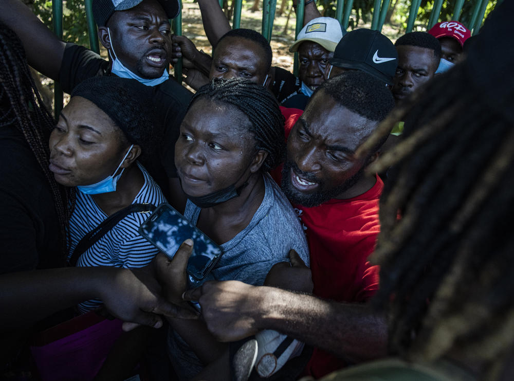 Haitian migrants jockey for position in line once they learn that there will no more buses for the rest of the day. Decades of political and economic instability have led Haitians to leave their country seeking better lives abroad.
