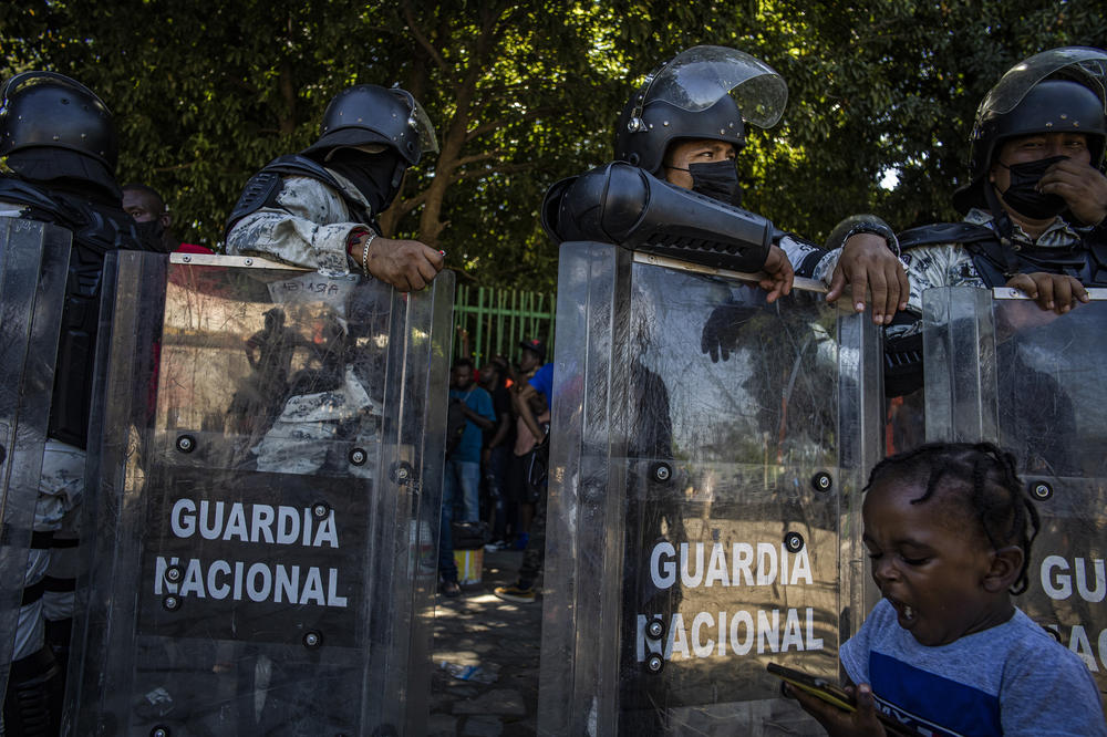 Mexican National Guard troops control the line of migrants waiting for buses in a Tapachula city park.