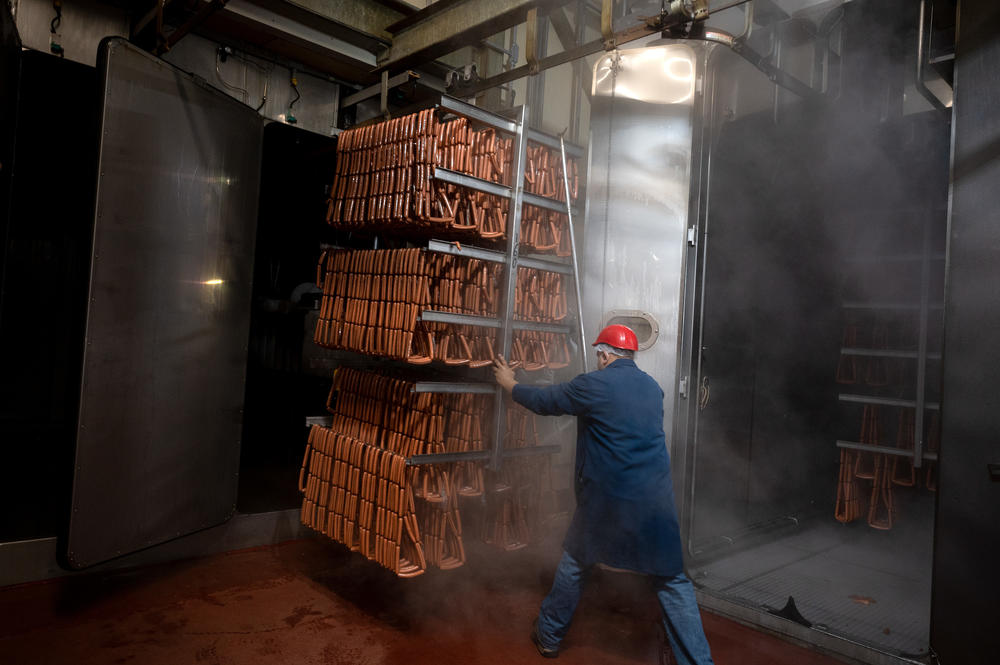 A worker moves a trolley of freshly cooked hot dogs into the cooling at the Hummel Bros. hot dog factory in New Haven, Conn., on July 1. <a href=